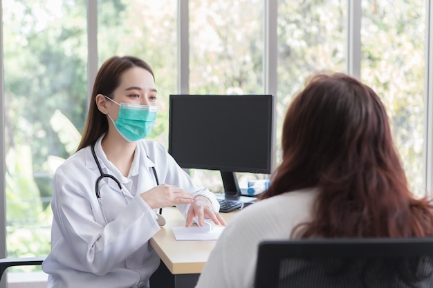 Une patiente asiatique âgée est contrôlée par un médecin professionnel tandis que les deux portent un masque médical à l'hôpital.