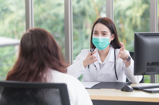 Une patiente asiatique âgée est contrôlée par un médecin tandis que les deux portent un masque médical à l'hôpital dans le cadre du concept de soins de santé et de protection contre les coronavirus