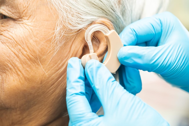 Patiente asiatique âgée portant un appareil auditif pour traiter un problème de perte auditive
