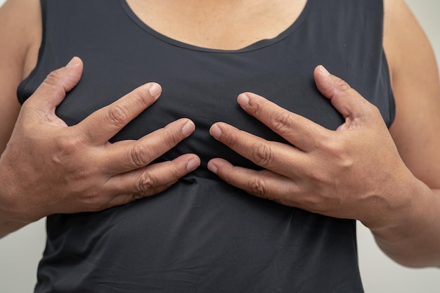 Une patiente asiatique vérifie et s'inquiète de son auto-examen des seins ou du symbole BES de la Journée mondiale du cancer du sein