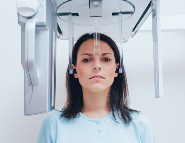 Patiente jeune femme debout dans une machine à rayons x.