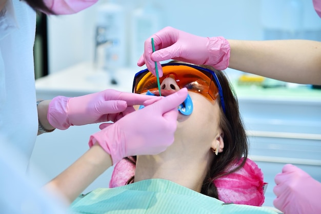 Patiente avec des lunettes de protection et un rétracteur pour la procédure de blanchiment des dents dans la clinique Concept de blanchissement dentaire et dentaire Close up