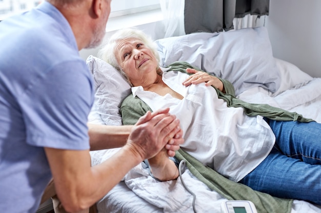 patiente mature à l'hôpital avec un mari inquiet tenant par la main tout en vérifiant la pression artérielle avec un tonomètre. l'homme aide, soutient