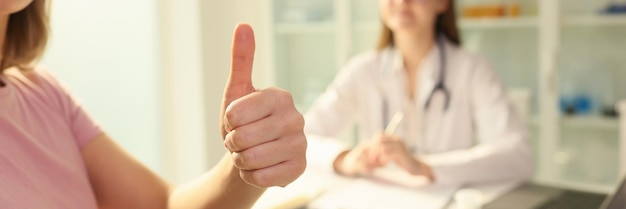 Une patiente montre le pouce levé alors qu'elle était assise près d'une femme médecin à la clinique de bons commentaires et