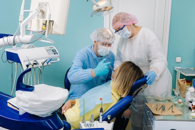 Une patiente portant des lunettes dentaires traite les dents chez le dentiste avec des obturations dentaires à lumière ultraviolette