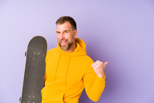 Patineur senior homme isolé sur les points du mur violet avec le doigt du pouce, rire et insouciant