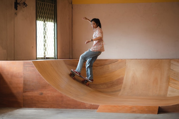 Patineuse de femmes asiatiques faisant des tours en sautant dans le garage souterrain Activité urbaine style de vie intérieur