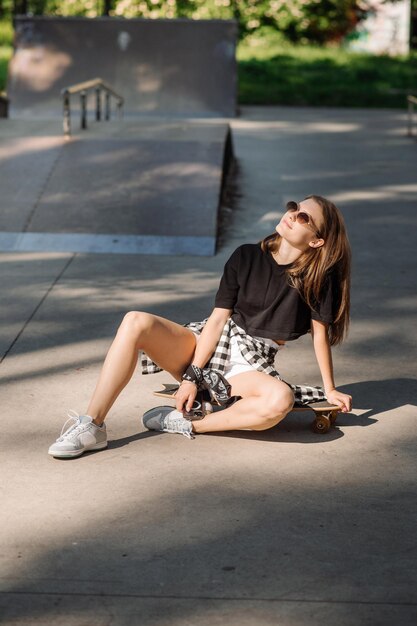 Patineuse avec une planche à roulettes relaxante dans la patinoire