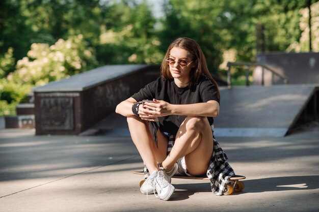 Patineuse avec une planche à roulettes relaxante dans la patinoire