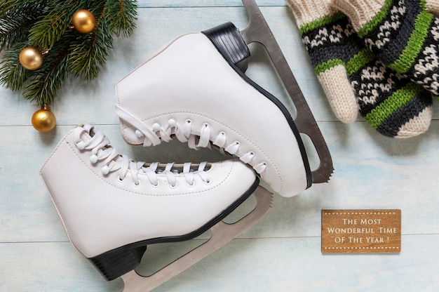 Photo patins blancs, mitaines tricotées et décorations de noël sur un fond bleu clair