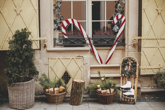 Patins à glace vintage élégants et couronne rustique sur une canne en bonbon de traîneau en bois à l'extérieur du bâtiment Décor de Noël rustique moderne dans la rue de la ville Vacances d'hiver en Europe Joyeux Noël