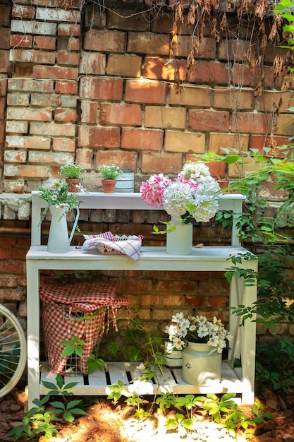 Patio de maison avec plantes, fleurs et vélo contre mur de briques sur terrasse dans jardin d'été