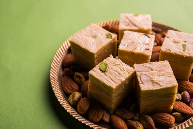 Patisa ou Soan Papdi est un dessert indien populaire en forme de cube floconneux et croustillant. Servi avec amandes et pistache dans une assiette sur fond de mauvaise humeur. Mise au point sélective