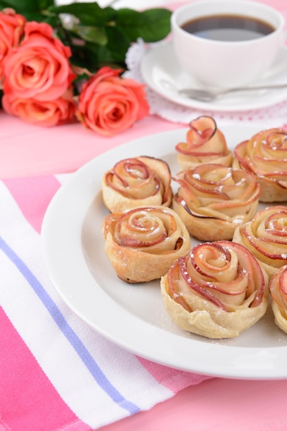 Photo pâtisserie bouffée savoureuse avec des roses en forme de pomme sur une assiette sur table en gros plan