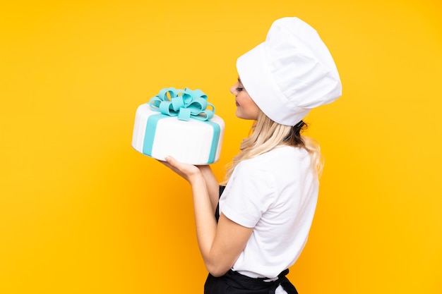 Pâtisserie fille adolescente tenant un gros gâteau