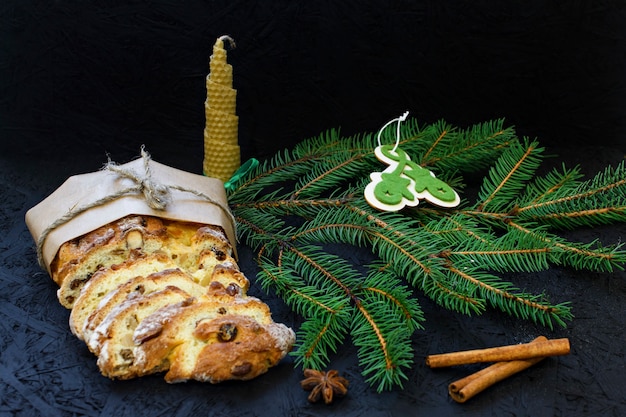 Pâtisserie de Noël allemande traditionnelle - stollen sur un fond noir avec des branches de sapin, spi