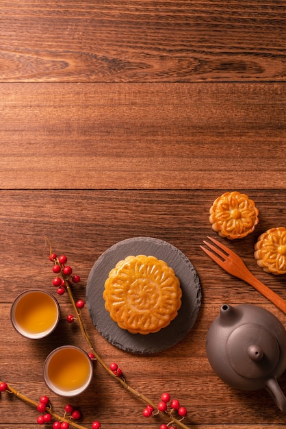 Photo pâtisserie traditionnelle chinoise mooncake mooncake avec des tasses à thé sur un plateau de service en bambou sur fond de bois pour la fête de la mi-automne, vue de dessus, mise à plat