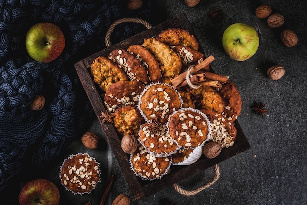 Pâtisseries automne hiver. Nourriture végétalienne. Biscuits maison sains, muffins aux noix, pommes, flocons d'avoine. Ambiance chaleureuse à la maison, couverture chaude, ingrédients. Table en pierre sombre. vue de dessus