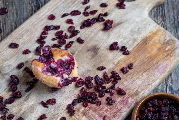 Des pâtisseries de blé avec garniture de fraise cerise rouge sur une planche de canneberges séchées séchées dans du sirop sucré traînent autour de la cuisson