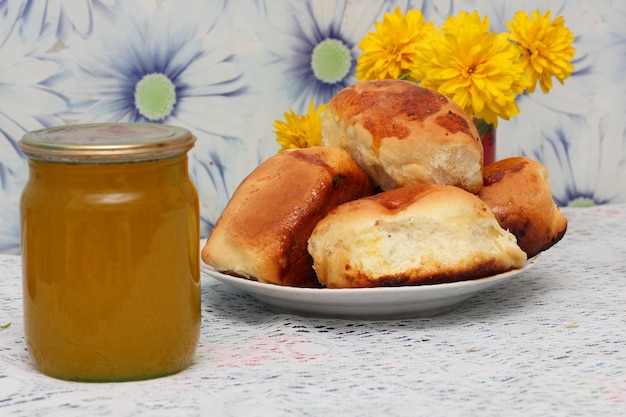 Pâtisseries pour le petit-déjeuner Assiette avec des tartes aux pommes sucrées et du miel sur la table Gros plan de tartes au miel et de fleurs jaunes dans la cuisine de grand-mère