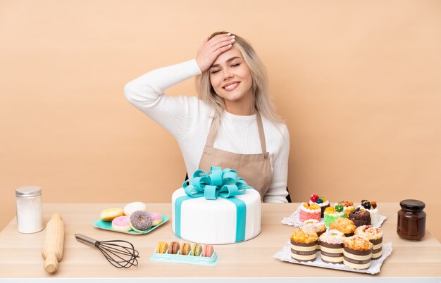 Pâtissier adolescent avec un gros gâteau dans une table en riant