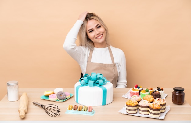 Pâtissier adolescent avec un gros gâteau dans une table en riant