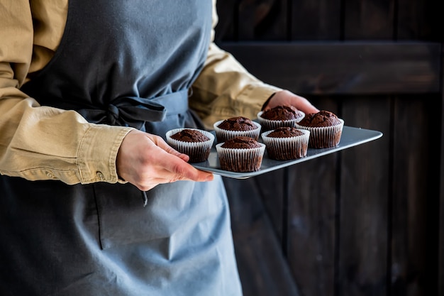 Pâtissier en tablier détient des cupcakes