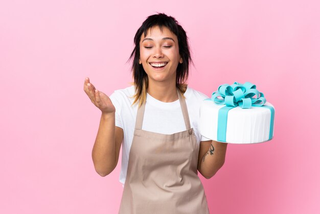 Pâtissier uruguayen tenant un gros gâteau sur rire rose isolé