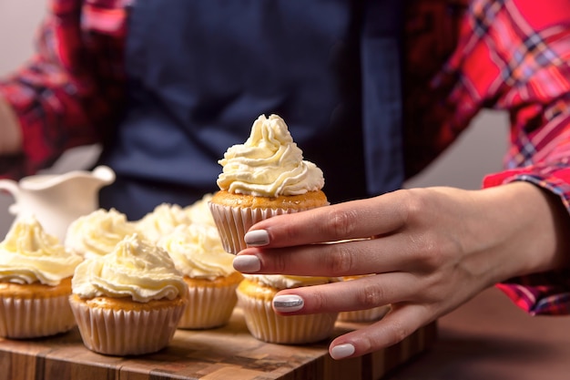 Une pâtissière dans un tablier bleu tient un cupcake au tiramisu