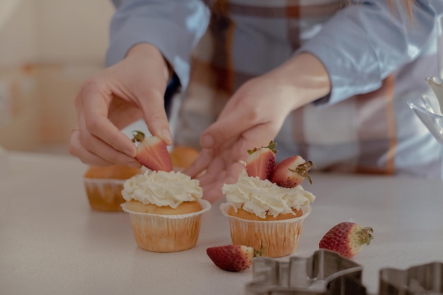 Photo une pâtissière décore des cupcakes avec des baies pour présenter ses produits de boulangerie faits maison.