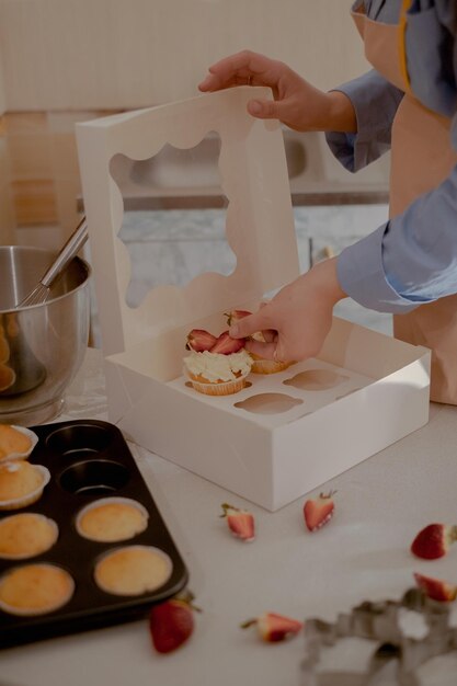 Une pâtissière met des cupcakes dans un emballage pour les expédier aux clients.