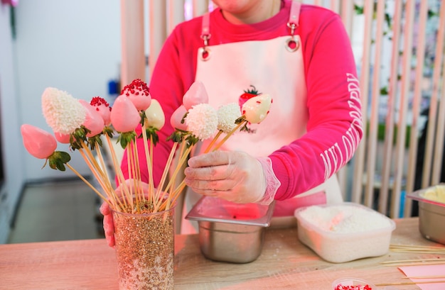 Une pâtissière ramasse un bouquet de fraises enrobées de chocolat. cadeaux sucrés