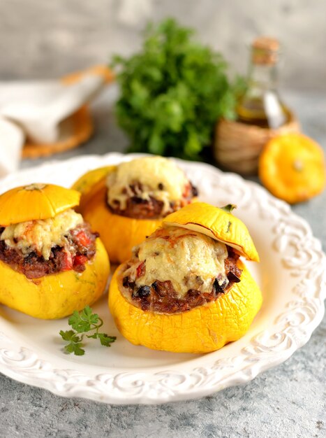 Patissons jaunes biologiques farcis de viande, oignons, carottes, champignons et poivrons rouges cuits au four avec du fromage.