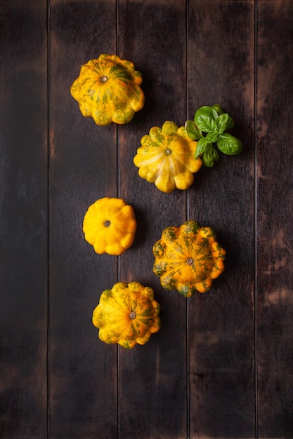 Patissons jaunes ou courge et une feuille de basilic sur un fond en bois marron