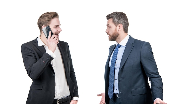 Patron en colère se disputant avec un employé souriant parlant au téléphone isolé sur un conflit blanc