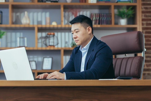 Patron d'homme d'affaires asiatique sérieux et pensif travaillant dans un bureau classique pensant à une solution