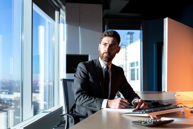 Photo patron d'homme d'affaires barbu sérieux travaillant à l'ordinateur dans un bureau moderne