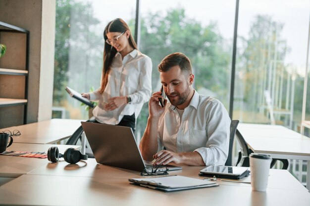 Le patron parle par téléphone L'homme et la femme travaillent ensemble dans le bureau moderne