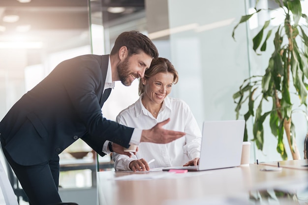 Patronne mature discutant d'un projet en ligne avec un employé