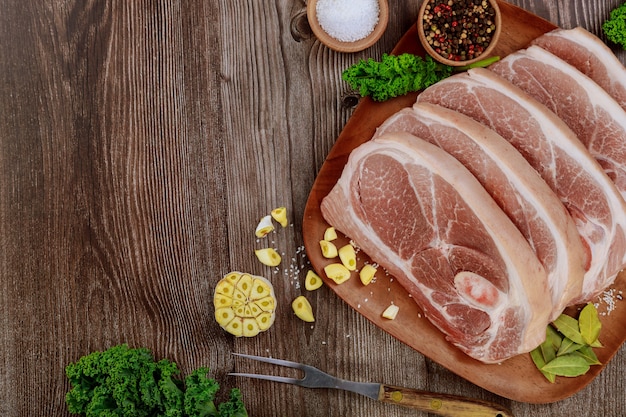 Épaule de porc cru en tranches avec la peau et les os sur la table en bois