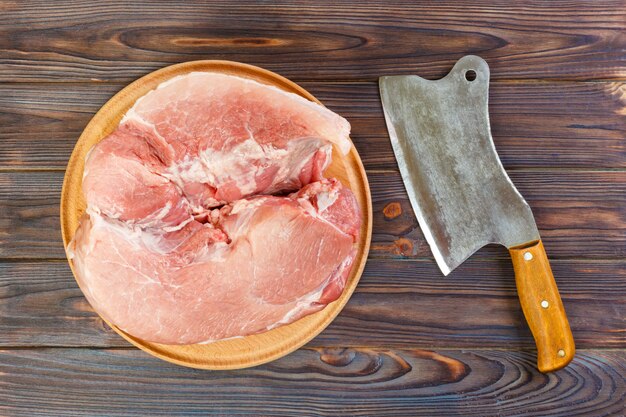 Épaule de porc crue à bord avec un couteau ou une hache de cuisine