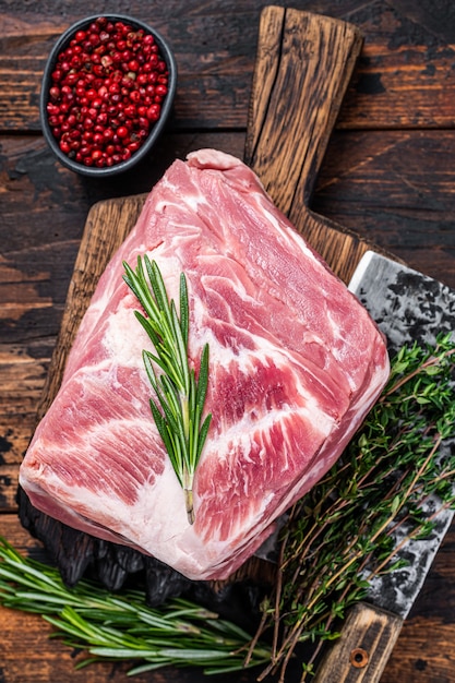 Épaule de porc viande crue pour steaks frais sur planche à découper en bois avec couperet de boucher