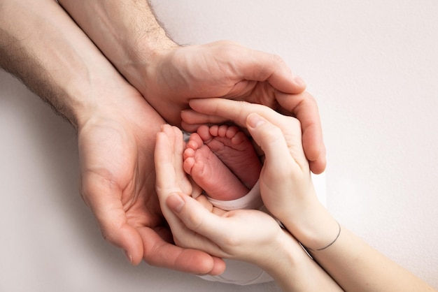 Les paumes du père la mère tiennent le pied du nouveau-né Pieds du nouveau-né sur les paumes des parents Photographie en studio des orteils des talons et des pieds d'un enfant Concept