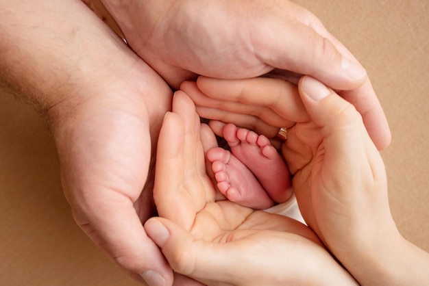 Les paumes des parents Un père et une mère tiennent les pieds d'un nouveau-né Les pieds d'un nouveau-né entre les mains des parents Photo des talons et des orteils