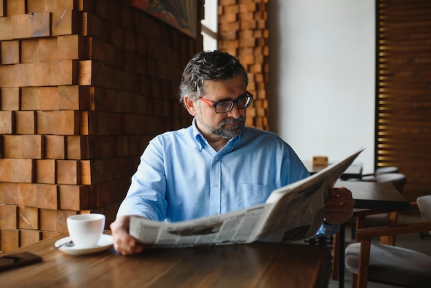 Pause-café homme buvant du café et lisant le journal au café-bar