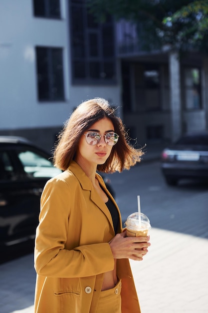 Pause-café Jeune femme à la mode en manteau de couleur bordeaux pendant la journée avec sa voiture