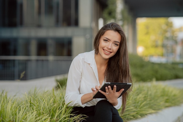 Pause du bureau une fille bien habillée est assise sur du béton à l'extérieur