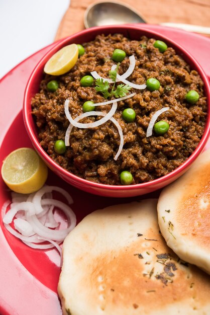 Pavé de mouton Kheema OU Viande hachée épicée indienne servie avec du pain OU du kulcha, garni de pois verts. fond de mauvaise humeur. Mise au point sélective