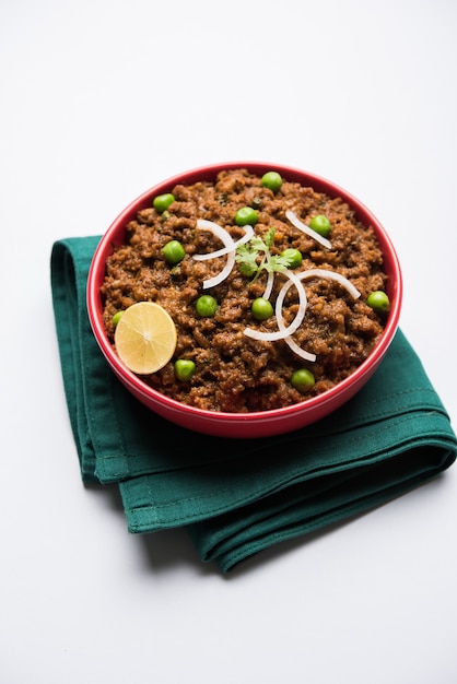 Pavé de mouton Kheema OU Viande hachée épicée indienne servie avec du pain OU du kulcha, garni de pois verts. fond de mauvaise humeur. Mise au point sélective