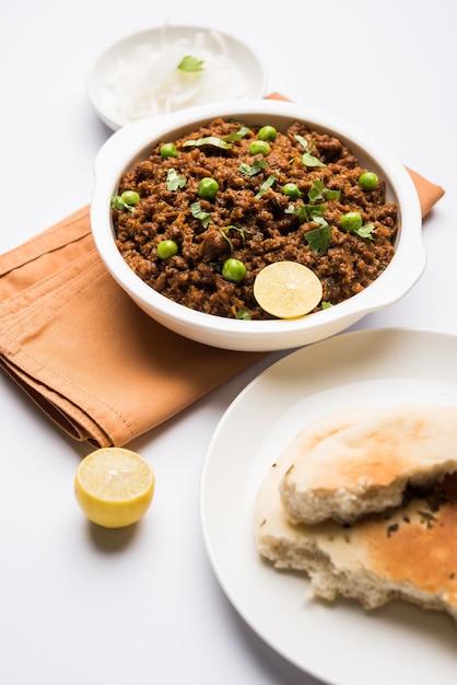 Pavé de mouton Kheema OU Viande hachée épicée indienne servie avec du pain OU du kulcha, garni de pois verts. fond de mauvaise humeur. Mise au point sélective